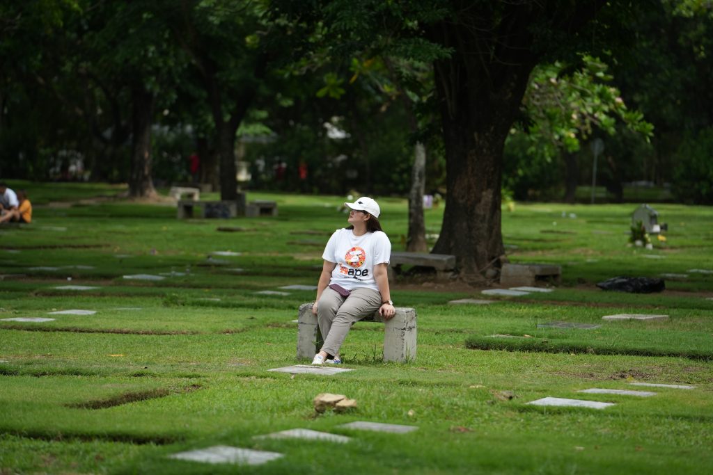 woman sitting on a bench in the middle of a memorial park.